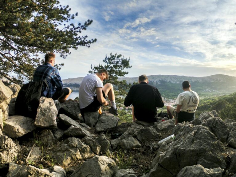 Four friends resting during a scenic hike in Jezerane, Croatia, surrounded by nature.